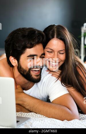 Un jeune couple se détendant à la maison avec un ordinateur portable. L'amour, le bonheur, les gens et le concept amusant. Banque D'Images