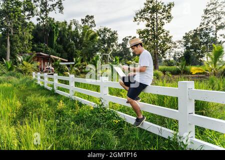 Homme asiatique freelance faisant appel téléphonique partager de bonnes nouvelles sur le projet de travail dans la nature, travail indépendant, Male aventure blogger. Banque D'Images