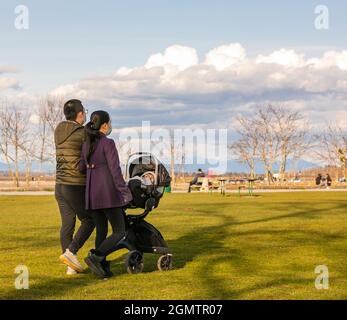 Couple asiatique marchant dans un parc avec leur bébé dans une poussette de cariage. Banque D'Images