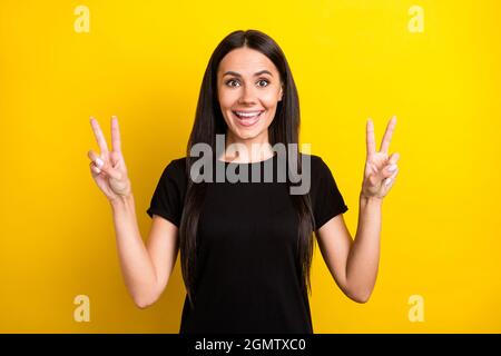 Photo de charmante dame gaie deux mains doigts montrent V-signe un sourire tortu isolé sur fond jaune Banque D'Images