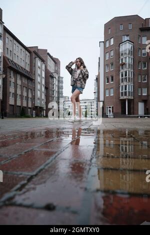 fille près de la flaque d'automne avec des réflexions sur la place de la ville Banque D'Images