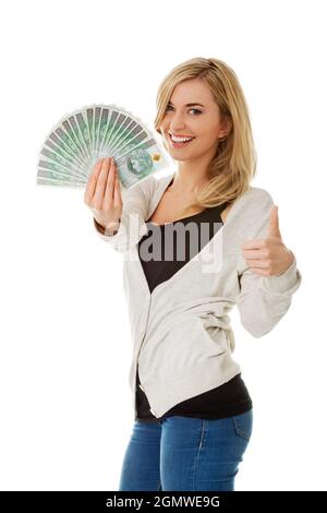 Femme polonaise joyeuse tenant des billets de banque avec le signe d'approbation isolé sur fond blanc Banque D'Images