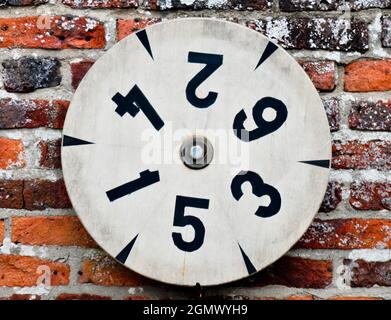 Roue de numéro tournant sur un vieux mur de briques rustique. Banque D'Images