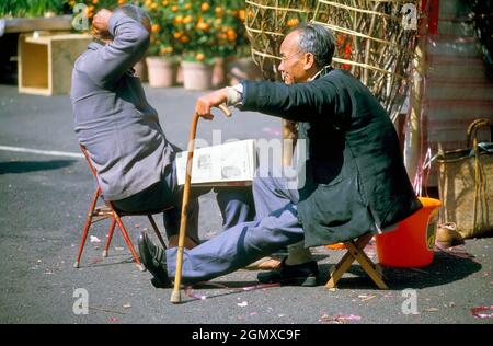 Hong Kong, Chine - 7 février 2006 ; deux vieux hommes en balle, assis et bavardant. Donner et recevoir des Kumquats est une tradition chinoise du nouvel an à Hong K Banque D'Images