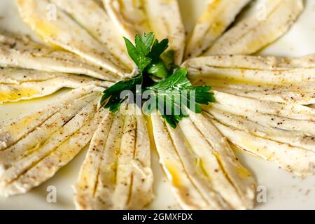 Anchois marinés au vinaigre, à l'huile d'olive, au poivre et au persil, dans une assiette, en gros plan Banque D'Images