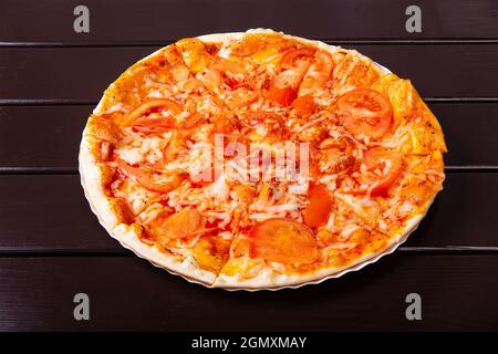 Une pizza rustique entière à Margarita avec mozzarella, tomate et basilic est servie sur une assiette en papier sur une table en bois Banque D'Images