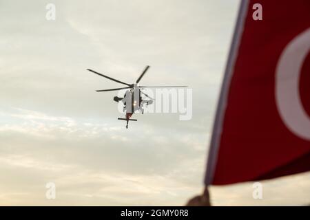 Izmir, Turquie - 9 septembre 2021 : hélicoptère de la police turque d'Atak et drapeau turc dans le même cadre lors des célébrations du jour de la libération d'Izmir Banque D'Images