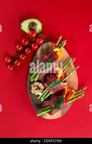 roulés de bœuf crus et garnitures de légumes frais prêts à cuire sur fond blanc. Banque D'Images