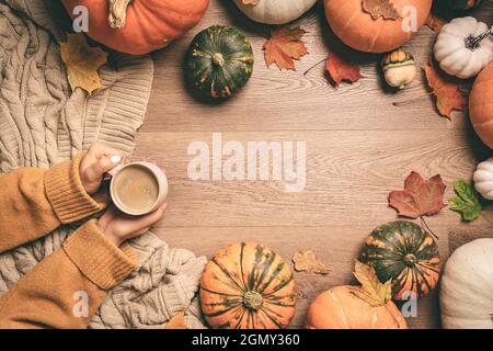 Femmes mains tenant le café chaud avec des citrouilles et des feuilles colorées arrière-plan vue de dessus. Elégante couche d'automne. Bonjour automne. Image chaleureuse et chaleureuse Banque D'Images