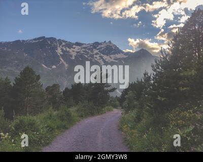 Une route de terre dans les montagnes. Magnifique paysage des montagnes du Caucase au coucher du soleil. Route de randonnée vide. Banque D'Images