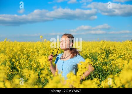 Belle jeune fille est souriante avec des fleurs jaunes dans le champ d'été Banque D'Images