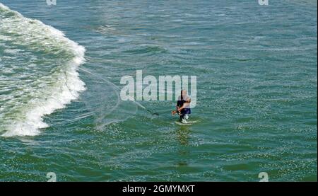 RIO DE JANEIRO, BRÉSIL - 25 MARS 2017 : pêche d'homme avec filet dans l'eau de la plage de Barra da Tijuca Banque D'Images