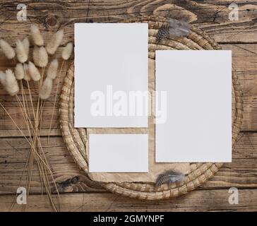 Cartes vierges de mariage sur une table en bois marron avec fleurs séchées et plumes autour de la vue du dessus. Scène de maquette de boho féminine avec modèles de cartes f Banque D'Images