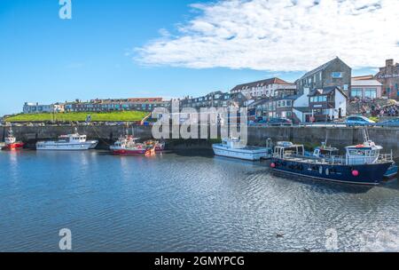 Bateaux de pêche et de plaisance amarrés à marée basse dans le port de Seahouses. Banque D'Images