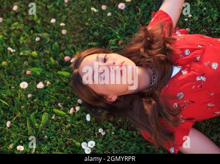 Jeune belle fille reposant sur l'herbe de printemps fraîche Banque D'Images