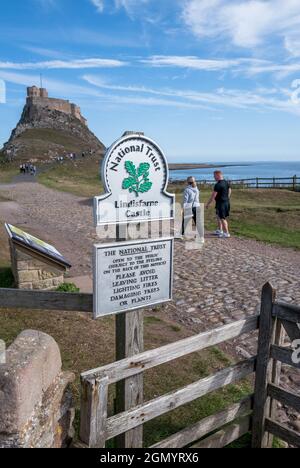 Touristes sur la route côtière en direction du château sur l'île Sainte o fLindisfarne, Northumberland, Angleterre. Banque D'Images