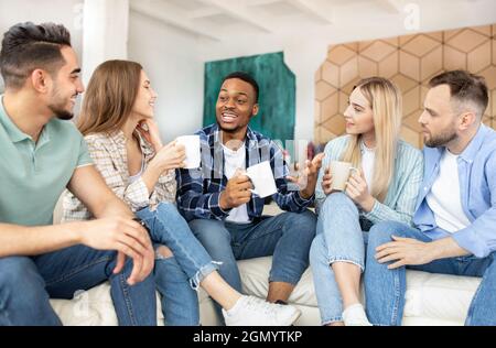 Groupe de jeunes du millénaire divers amis discutant, ayant plaisir à la fête des étudiants, passant le week-end ensemble à la maison Banque D'Images