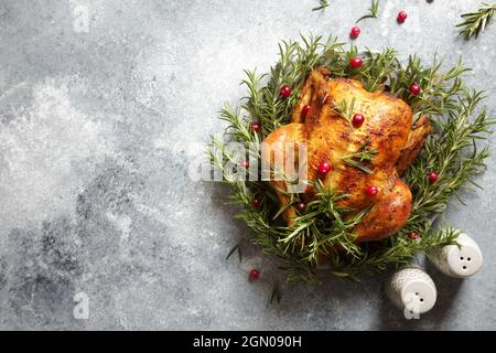 poulet entier cuit avec ail au romarin et canneberges sur fond de béton gris. poulet rôti. Banque D'Images