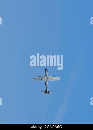 Avion à hélice vu d'en bas lors d'un vol voltige acrobatique contre un ciel bleu clair. Banque D'Images