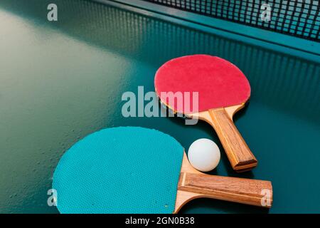 Raquettes de tennis de table et balles de ping-pong sur une surface de table verte avec filet, mise au point sélective Banque D'Images