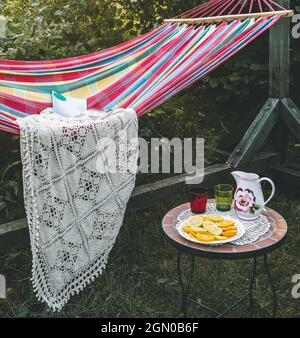 Coin détente dans le jardin. Cadre extérieur en été. Hamac. Tranches d'orange, de verres et de carafe sur une petite table basse. Banque D'Images