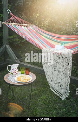 Coin détente dans le jardin. Cadre extérieur en été. Hamac. Tranches d'orange, de verres et de carafe sur une petite table basse. Banque D'Images