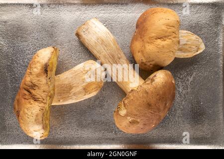 Trois champignons porcini forestiers sur un plateau métallique, vue rapprochée du dessus. Banque D'Images