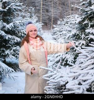 Une femme choisit un arbre de Noël dans la pépinière en nature d'hiver à la Saint-Sylvestre Banque D'Images