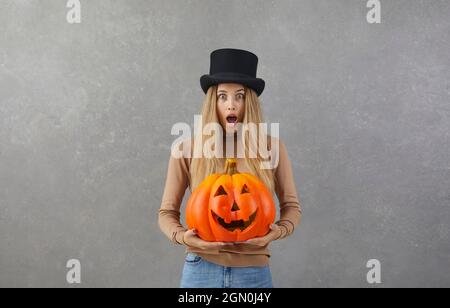 Femme avec la citrouille d'Halloween regardant l'appareil photo avec l'expression de visage choqué et effrayée Banque D'Images