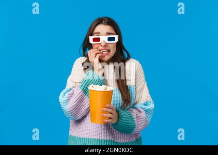 Portrait de taille haute fille de brunette étonnante et effeuillée en hiver chandail, regarder film effrayant, première dans le cinéma, porter des lunettes 3d, mordant Banque D'Images