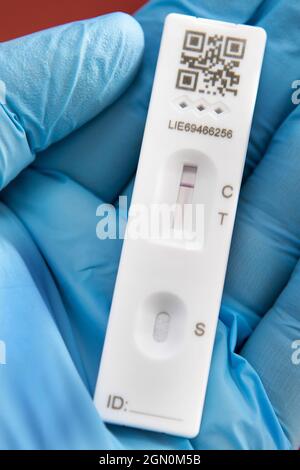 Gants médicaux bleus portant une bandelette de test de débit latéral à résultat négatif Covid 19 Banque D'Images