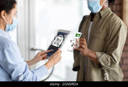 Femme travailleur avec Digital Tablet Scanning Health Code QR de visiteur masculin Banque D'Images