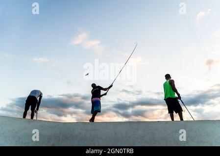 Salvador, Bahia, Brésil - 23 mai 2021 : silhouette de pêcheurs avec leurs poteaux au coucher du soleil. Banque D'Images