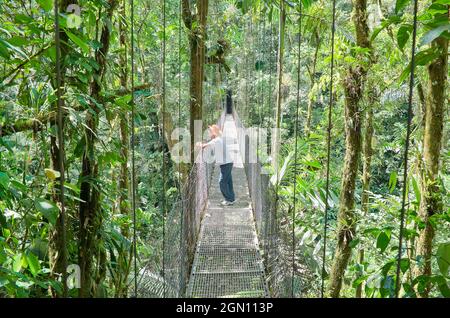 Homme debout sur le pont suspendu, Parc national du volcan Arenal, la Fortuna, Costa Rica Banque D'Images
