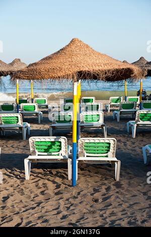 Magnifique plage de sable avec chaises longues sous des parasols de plage de paille à Malaga, Espagne Banque D'Images