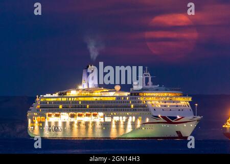 Weymouth, Dorset, Royaume-Uni. 21 septembre 2021. Météo Royaume-Uni. La Lune de moisson est occultée par de minces nuages hauts alors qu'elle s'élève derrière le bateau de croisière P&O Aurora qui est ancré dans la baie de Weymouth à Dorset le dernier jour de l'été astronomique. Crédit photo : Graham Hunt/Alamy Live News. Banque D'Images