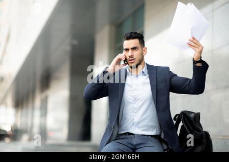 Homme d'affaires du Moyen-Orient en colère ayant une conversation téléphonique dans la rue Banque D'Images