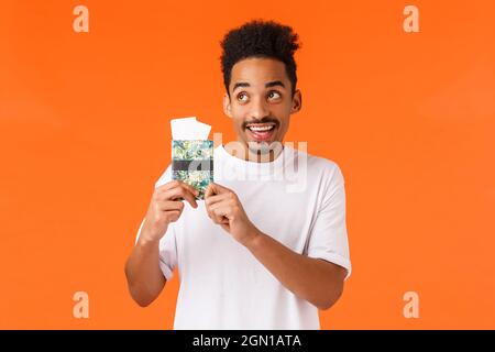 Joyeux, charmant et charmant touriste afro-américain, hôtel réservé, avec deux billets pour un passeport, petite amie dans le terminal de l'aéroport Banque D'Images