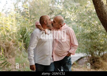 Couple d'âge mûr gay s'embrassant tout en appréciant un moment romantique ensemble dans un parc. Banque D'Images