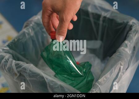 Un homme a mis la bouteille de plastique usagée à la main dans un bac de récupération des déchets séparé, puis recyclez-la Banque D'Images