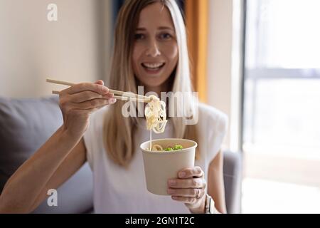 Bonne jeune femme d'affaires caucasienne avec des cheveux blonds portant des vêtements décontractés et a un déjeuner de l'assiette en papier avec des aliments sains pour le bien-être et Banque D'Images