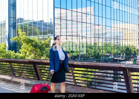 Femme d'affaires caucasienne de taille moyenne avec valise dans la ville Banque D'Images