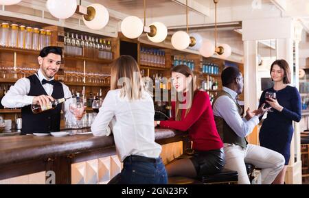 Portrait du barman et des personnes qui se tiennent près du comptoir du bar dans un restaurant luxueux Banque D'Images