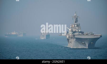 DÉTROIT D'HORMUZ (SEPT 17, 2021) le navire d'assaut amphibie USS Essex (LHD 2), à droite, et le navire de fret et de munitions sec USNS Wally Schirra (T-AKE 8), transitent le détroit d'Hormuz en formation derrière le quai de transport amphibie USS Portland (LPD 27). Portland et la 11e unité expéditionnaire maritime sont déployées dans la zone d'opérations de la 5e flotte des États-Unis afin d'assurer la stabilité et la sécurité maritimes dans la région centrale, reliant la Méditerranée et le Pacifique à travers l'océan Indien occidental et trois points d'étranglement stratégiques. (É.-U. Photo du corps marin par Sgt. Alexis Banque D'Images