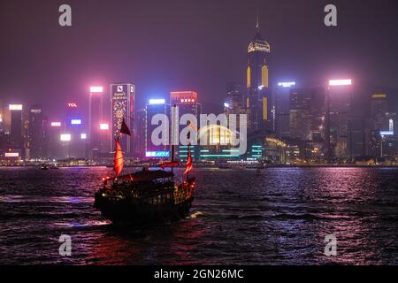 La jonque traditionnelle sert de bateau touristique dans le port de Victoria avec les gratte-ciel de Hong Kong derrière lui la nuit, Hong Kong, Hong Kong, Chine, Banque D'Images