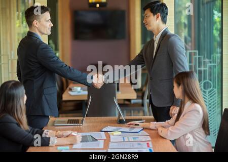 Image des gens d'affaires qui se secouent dans la salle du conseil après avoir fait affaire. Partenaire d'affaires, négociation, réunion d'affaires Banque D'Images