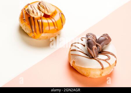 Gros plan de 2 beignets décorés de biscuits et dessinés avec du chocolat noir. La photo est prise en format horizontal et a un espace de copie. Banque D'Images