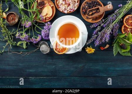 Une tasse de thé avec des fruits secs, des fleurs, et des herbes, tiré du dessus sur un fond rustique foncé en bois avec un endroit pour le texte Banque D'Images