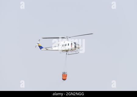 Hélicoptère d'urgence des pompiers effectuant un vol de ravitaillement en eau dans une zone urbaine Banque D'Images