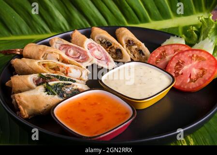 assiette noire avec une fusion de rouleaux de printemps, avec sauce au piment doux et mayonnaise Banque D'Images